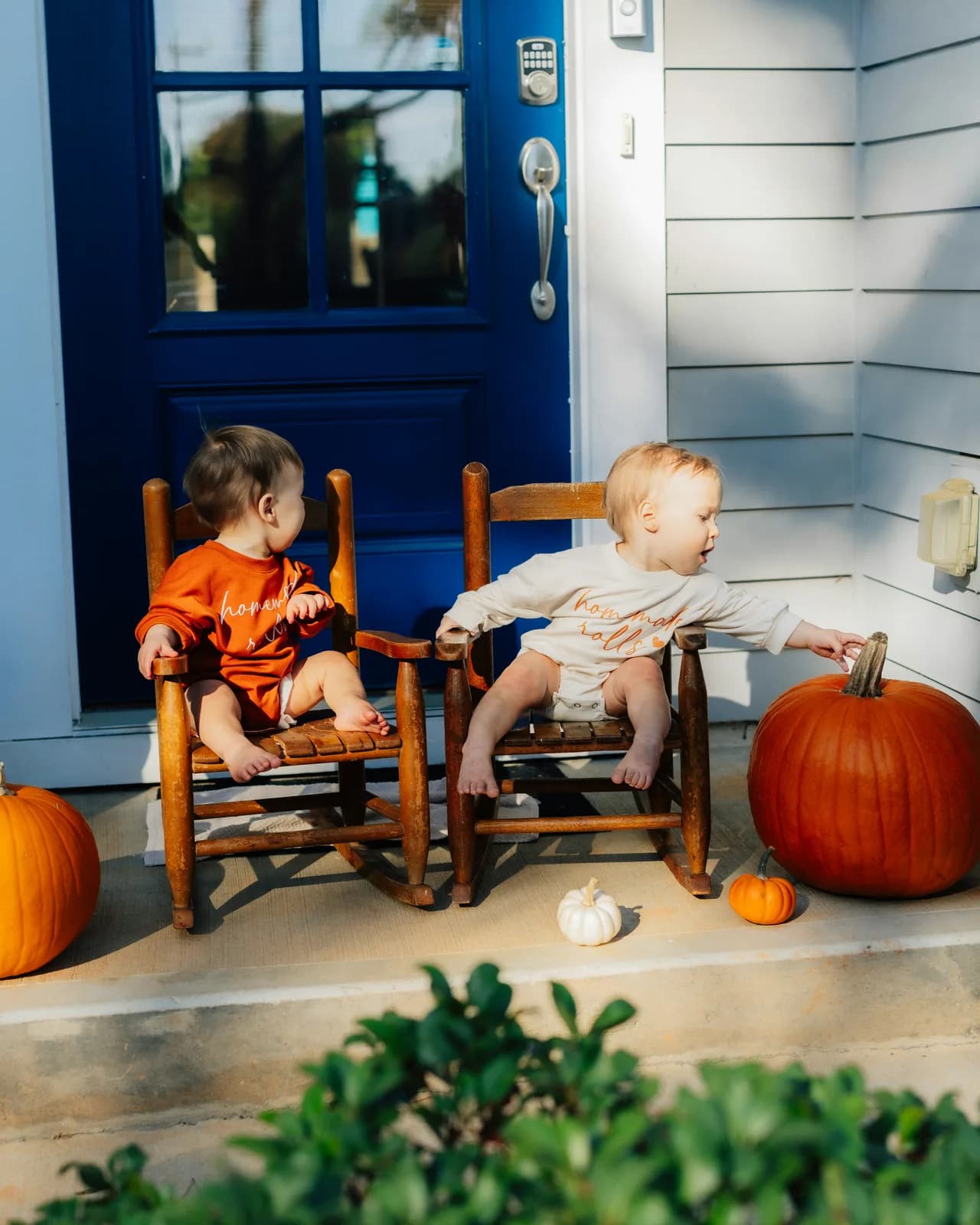 Two toddlers on a home's front porch in fall